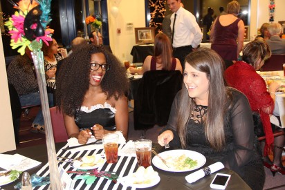 (Right) Kayton Abbott, Mesalands Community College Foundation Coordinator, socializes with one of the actresses playing the role of a maid, during the ‘Murder at the Masquerade’ fundraiser.