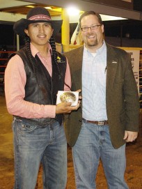 Caption. State Representative, Dennis Roch, presents Mesalands Community College Rodeo Team Member Edmiles Harvey of Tsaile, AZ, with his bareback riding championship buckle at the on-campus Mesalands Intercollegiate Rodeo Competition.
