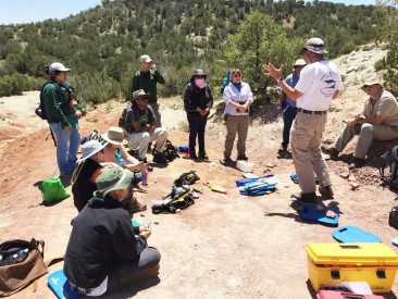 Students from McClellan Community College listen to (right) Dr. Axel Hungerbuehler, Faculty, Natural Sciences/Museum Curator at Mesalands, during a summer paleontology field class. Students excavated dinosaur-age fossils and processed them at the Mesalands Dinosaur Museum.