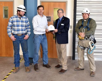 President Dr. Newsom and Wind Energy Technology Faculty Andy Swapp (right) and  Terrill Stowe present Senator Heinrich with a hard hat from the College.