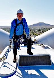 Dr. Thomas W. Newsom, President of Mesalands Community College, stands on the nacelle at the top of the North American Wind Research and Training Center turbine with Tucumcari Mountain visible in the background.