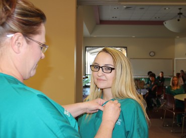 (Left) Jeanne Moralez, Allied Health Faculty Member for Mesalands Community College, gives Anastasia Schmitt, Mesalands graduate, her Allied Health pin during the Pinning Ceremony.