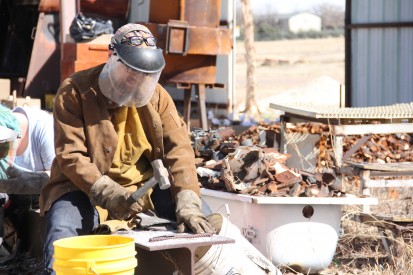 A Fine Arts student at Mesalands Community College, uses a hammer to break up the pieces of iron in preparation of the